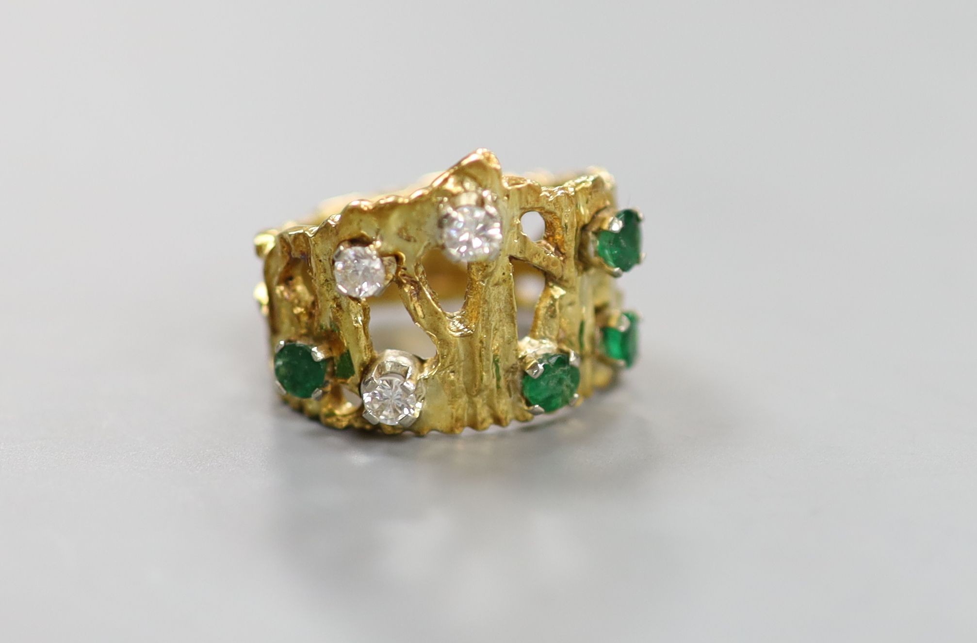 A pierced and textured 18ct, emerald and diamond set dress ring, size J, gross weight 8.3 grams.